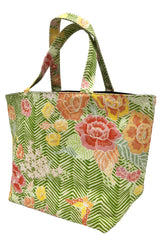 A fabric tote bag featuring a green and white chevron pattern overlaid with a colorful floral print in pink, orange, yellow, and white, complete with matching shoulder straps.